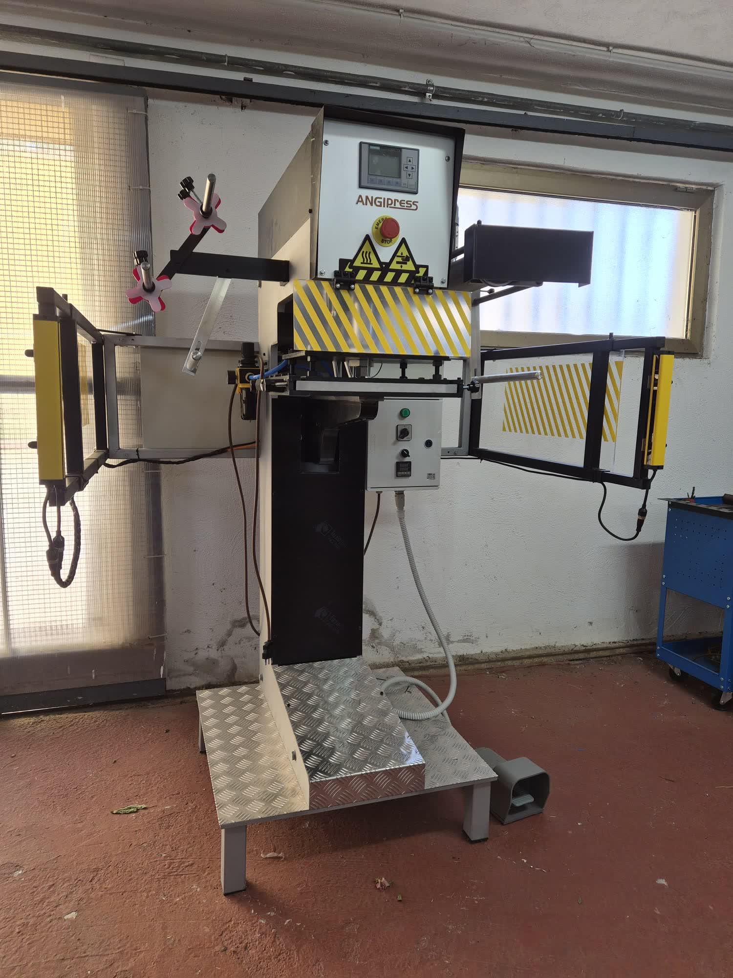 Macchina per stampa a caldo ANGIPRESS vista di fronte, con quadro comandi e barriere di sicurezza